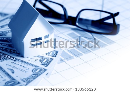 Business concept. Paper house near spectacles on one dollar bank notes on paper with chart