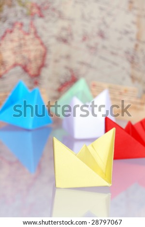 Colorful paper boats on background with old map