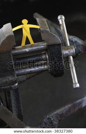 Small yellow paper man under pressure with old vise grip on abstract industry background