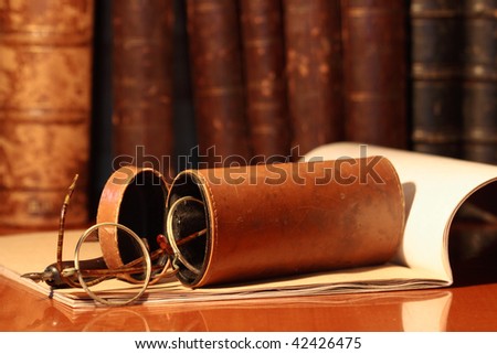Closeup of old spectacles inside leather case on background with book