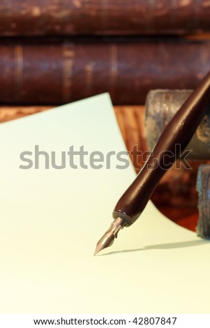 Ancient fountain pen on vintage background with paper sheet and old books