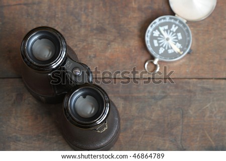 Still life with antique binoculars and compass on wooden background