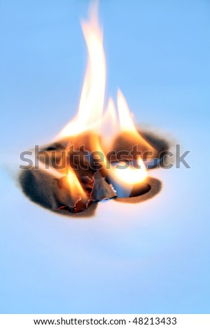 Fire flame inside hole of blue paper sheet