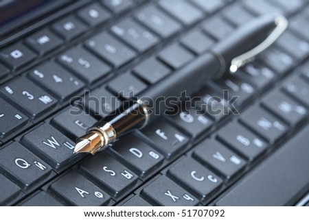 Closeup of fountain pen lying on black computer keyboard