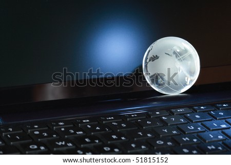 Closeup of glass globe lying on black computer keyboard