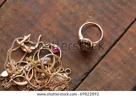 Closeup of pile of gold jewelry on wooden surface with copy space