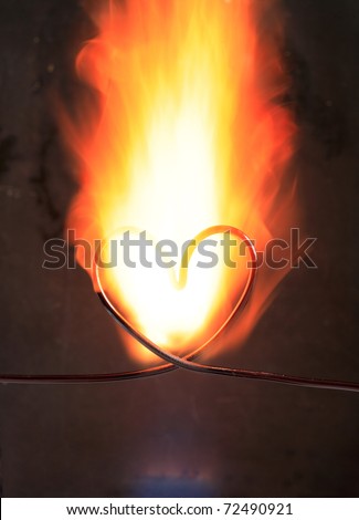 Heart made from wire in fire on dark background
