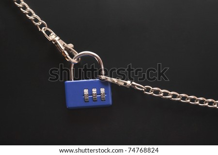Blue combination padlock hanging on black background with metal chains