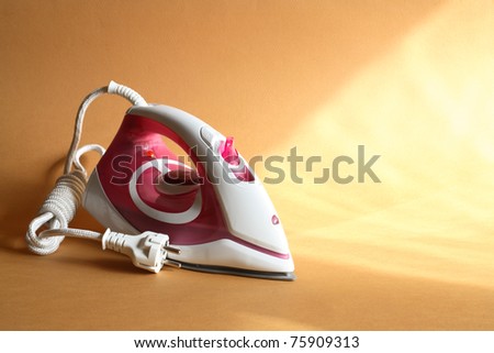 Modern electric iron standing on nice gold background with sun beam