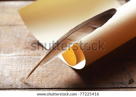 Vintage still life with blank scroll and quill on wooden surface