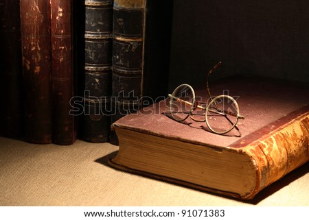 Vintage still life with old books and spectacles on canvas surface