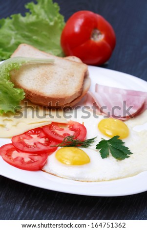 Closeup of plate with fried eggs, toasts and cheese near fork and knife
