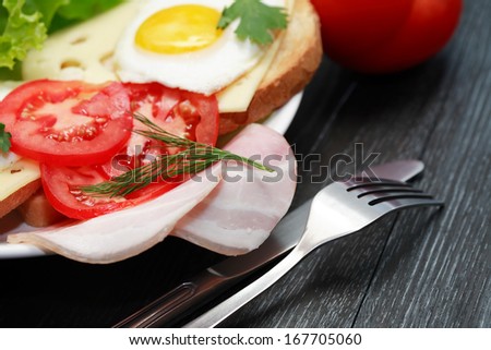 Closeup of plate with fried eggs and ham, toasts and cheese