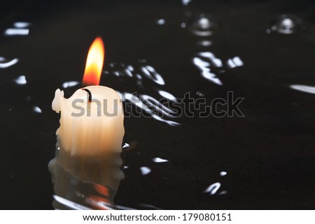 One lighting candle on dark water background with free space for text