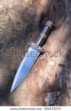 Ancient Roman military dagger on wooden background