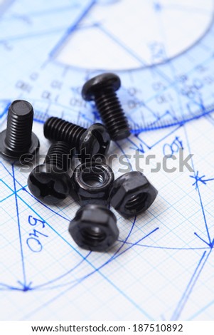 Industry concept. Set of black bolts and screw-nuts on graph paper with chart