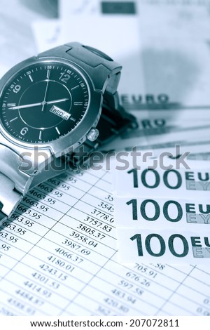 European Union Currency near wristwatch on paper background with digits table