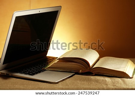 Education concept. Open laptop with blank screen near old book