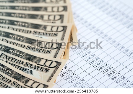 Bookkeeping concept. Closeup of dollar bank notes on paper list with digits