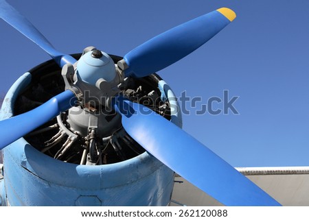 Closeup of old airplane engine with propeller against blue sky