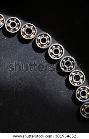 Industrial concept. Set of few ball bearings with shadow under sunlight on dark metal background