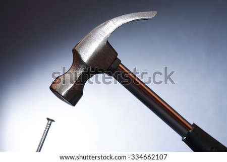 Work tool. Metal hammer above nail on nice dark background