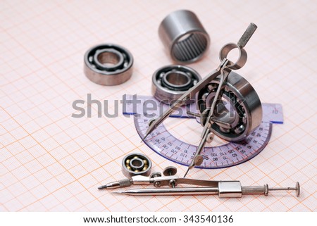 Industrial concept. Drawing instrument near ball bearing on graph paper background
