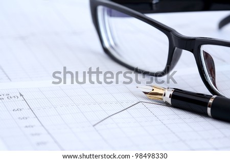 Business concept. Closeup of fountain pen and spectacles on graph paper with diagram