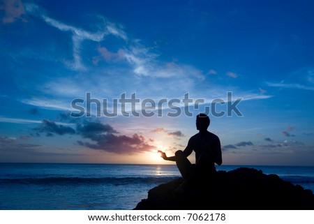 Silhouette of a man sitting on the rock, meditating (and keeping the sun)