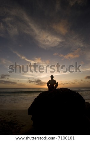 Silhouette of a man meditating on the rock.