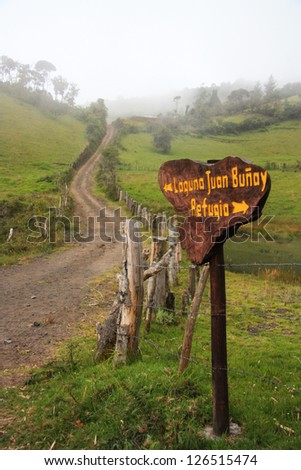 Dirt road surounded by fields, road sign to Refuge in case of volcano eruption. Ecuador.