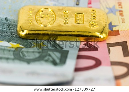 Gold bar standing on euro bank notes