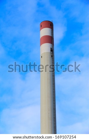 Tall white and red chimney, no smoke, on blue cloudy sky. Vertical, nobody