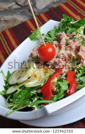 Tuna salad on white plate.. Delicious flaked tuna with cherry tomatoes, red peppers, and rocket or arugula leaves
