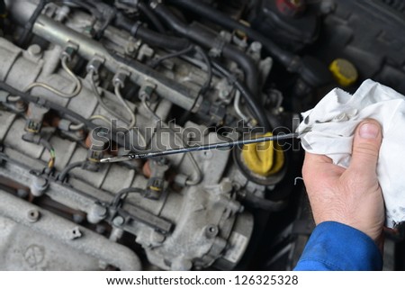 Auto mechanic checking engine oil level.