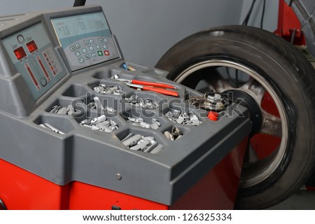 Wheel Balancing, Technician spins a car wheel as he waits for the machine to tell him he\'s reached the right spot to add a balancing weight.