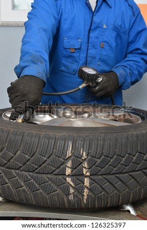 Auto mechanic is checking air pressure in tire