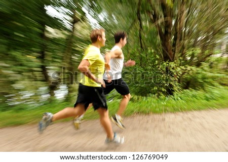 Two young athletes jogging / running in the park, Motion blurred