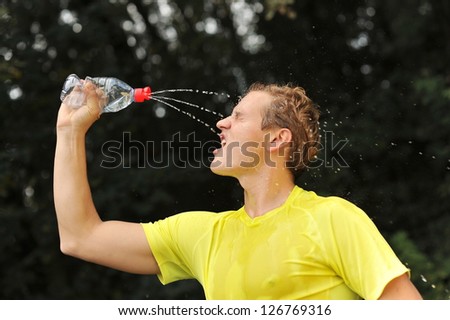 Young man athlete refresh himself and drinking water after running