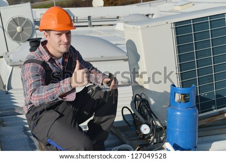 Air Conditioner Repairman Thumbs up, repairman working on a compressor and giving a thumbs up. Model is actual electrician.