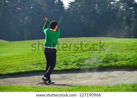 Golfer chipping the ball from sand trap, golf ball in the air.