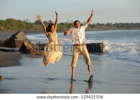 Happy just married young couple celebrating and have fun at beautiful beach sunset on Bali island, Indonesia