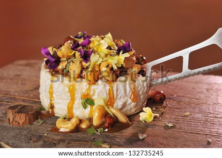 Grilled soft brie / Camembert cheese with honey, cashew nuts, almonds, walnuts and rosemary on an old board.