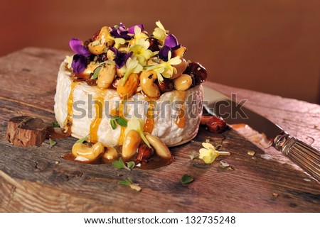 Grilled soft brie / Camembert cheese with honey, cashew nuts, almonds, walnuts and rosemary on an old board.