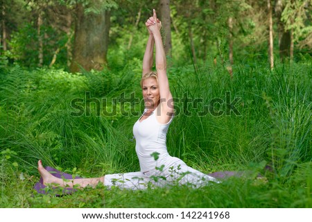 Beautiful young woman doing yoga outside in natural environment