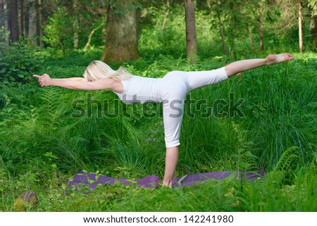 Beautiful young woman doing yoga outside in natural environment