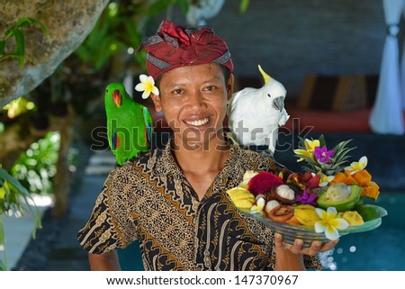 Asian Waiter With A Tray Of Tropical Fruits In An Exotic Setting. Shoot In A Luxury Resort On Bali Island, Indonesia