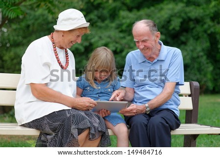 Grandmother, grandfather and granddaughter using tablet computer