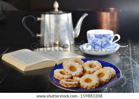 Delicious jam cookies with cup of English tea and book