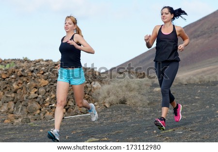 Two female running athletes. Women trail runner sprinting for success goals and healthy lifestyle in amazing nature landscape.